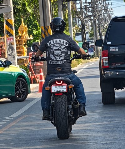 A rider in club colours on a motorcycle in traffic.