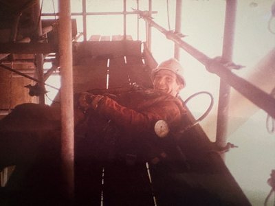 A technician working on ropes beneath a platform deck.